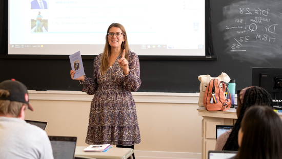 Heather Knorr leading a Spanish class at UNC-Chapel Hill. She's holding a book past students wrote in a prior year's class.